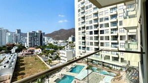 Un edificio alto con área de piscina, incluyendo una barandilla de cristal y sillas de descanso.