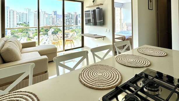 Una cocina moderna con una isla grande, un comedor con sillas blancas y un sofá.