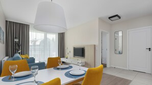 Een moderne hotelkamer met een eethoek, een bank, een televisie en een deur.