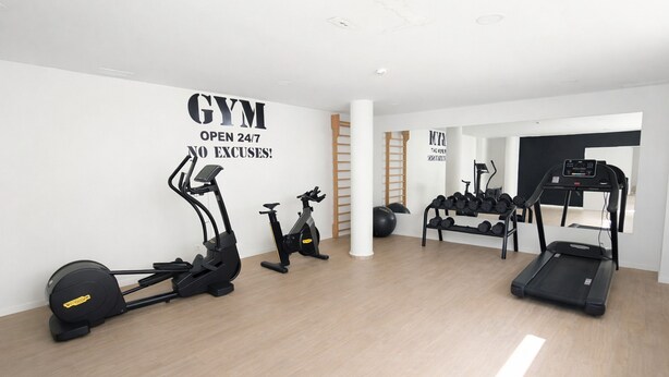 Uma academia com máquinas de cardio, pesos livres e esteira.