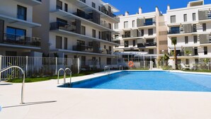 Um edifício de apartamentos moderno com piscina, varandas e área cercada.