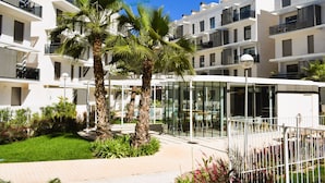 Um hotel moderno com paredes exteriores brancas, várias varandas e uma área de refeições com paredes de vidro.