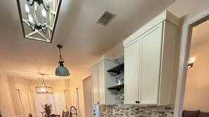 Una cocina moderna con una isla central, armarios blancos y salpicadero de azulejos.