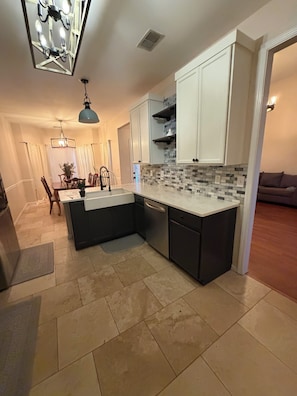A modern kitchen with a central island, white cabinetry, and a tiled backsplash.