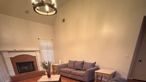 Una sala de estar con chimenea, un sofá, una mesa de centro y un sillón tapizado.