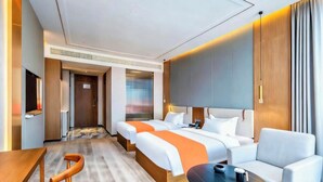 Quarto de hotel com duas camas, um sofá, uma mesa e uma televisão.