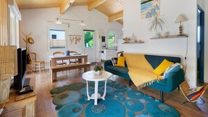 A spacious living area with a wooden ceiling, a sofa with yellow cushions, a dining table, and a television. - Wooden Country Holiday Home with Private Terrace, Wi-Fi, and Air Conditioning (Corme-Royal)