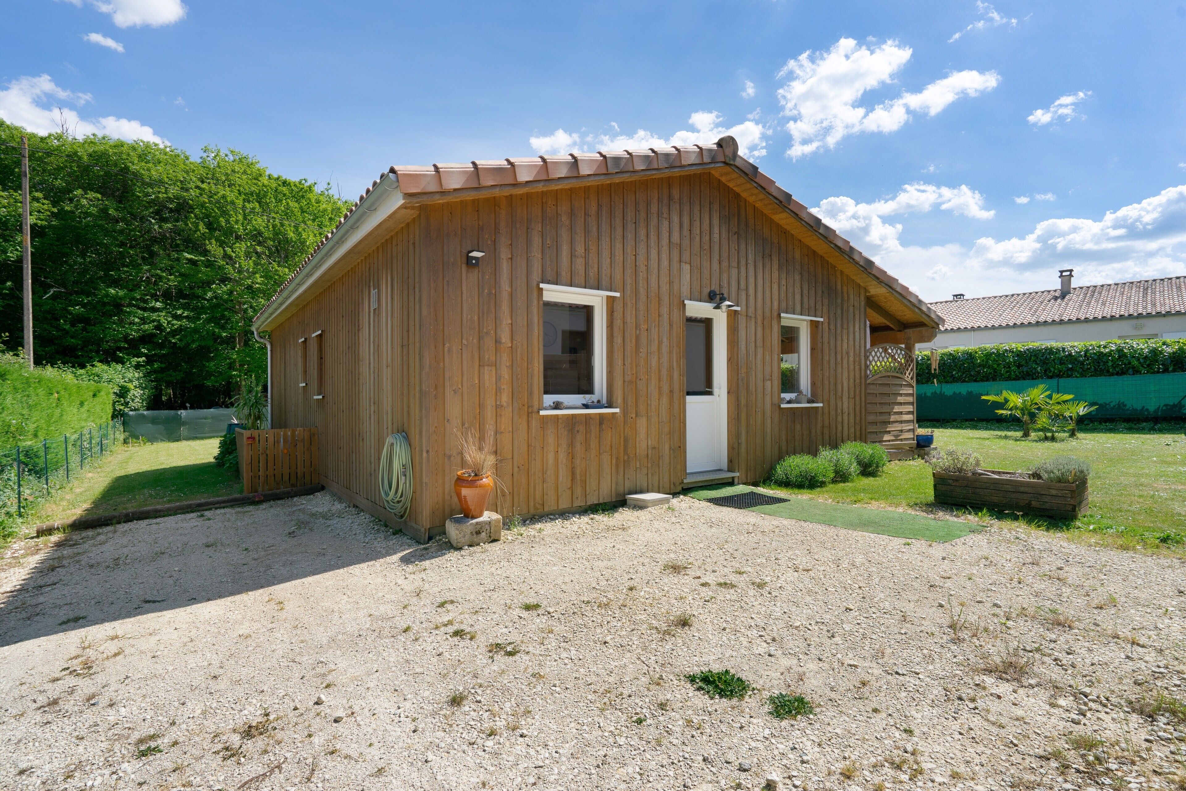 A wooden cabin with a door, two windows, and a gravel driveway.