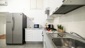 Eine moderne Küche mit einem Edelstahl-Kühlschrank, einer Mikrowelle, einem Gasherd und einem Spülbecken.