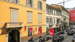 A yellow building with multiple windows, a red banner, and a tram line. - Italianway Comfort - Dell'Orso 9 B (Milan)