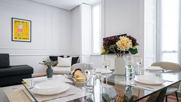 A modern dining room with a glass table set for a meal, a vase of flowers, and a painting on the wall. - Italianway Comfort - Dell'Orso 9 B (Milan)