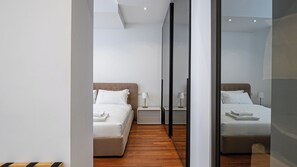 A modern hotel room with two beds, a wooden floor, and a mirror reflecting the room. - Italianway Comfort - Dell'Orso 9 B (Milan)