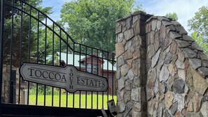 A gated entrance with a stone wall and a sign reading 'TOCOA ESTATES.' - Tranquility Cabin: Secluded Mountain Escape with Game Room, Fire Pit & Hot Tub (Blue Ridge)