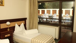 A hotel room with a bed, a nightstand, a lamp, a window with a view of an outdoor seating area. - Hotel President Scornicesti (Scornicesti)