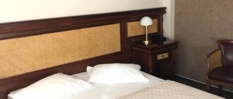 A hotel room with a bed, a nightstand, a lamp, a chair, and a painting on the wall.