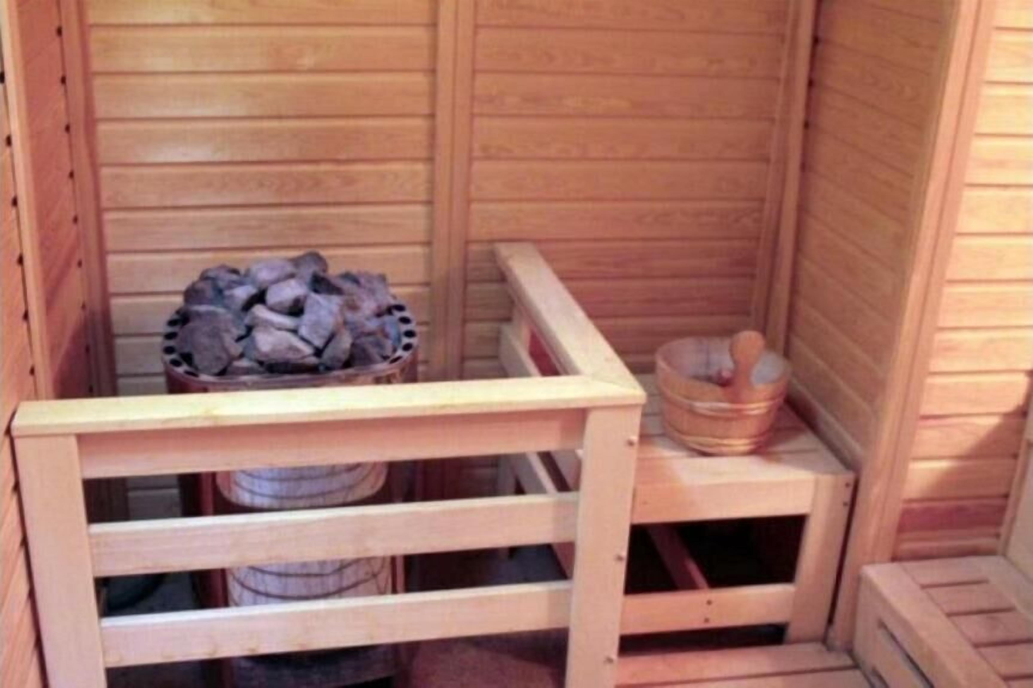 Eine Holzsauna mit einer Sitzbank, einem Eimer und einem Steinhaufen.