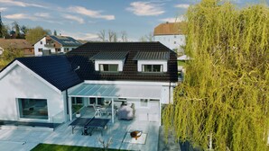 Een modern huis met een schuin dak, een glazen conservatorium en een tafeltennistafel.