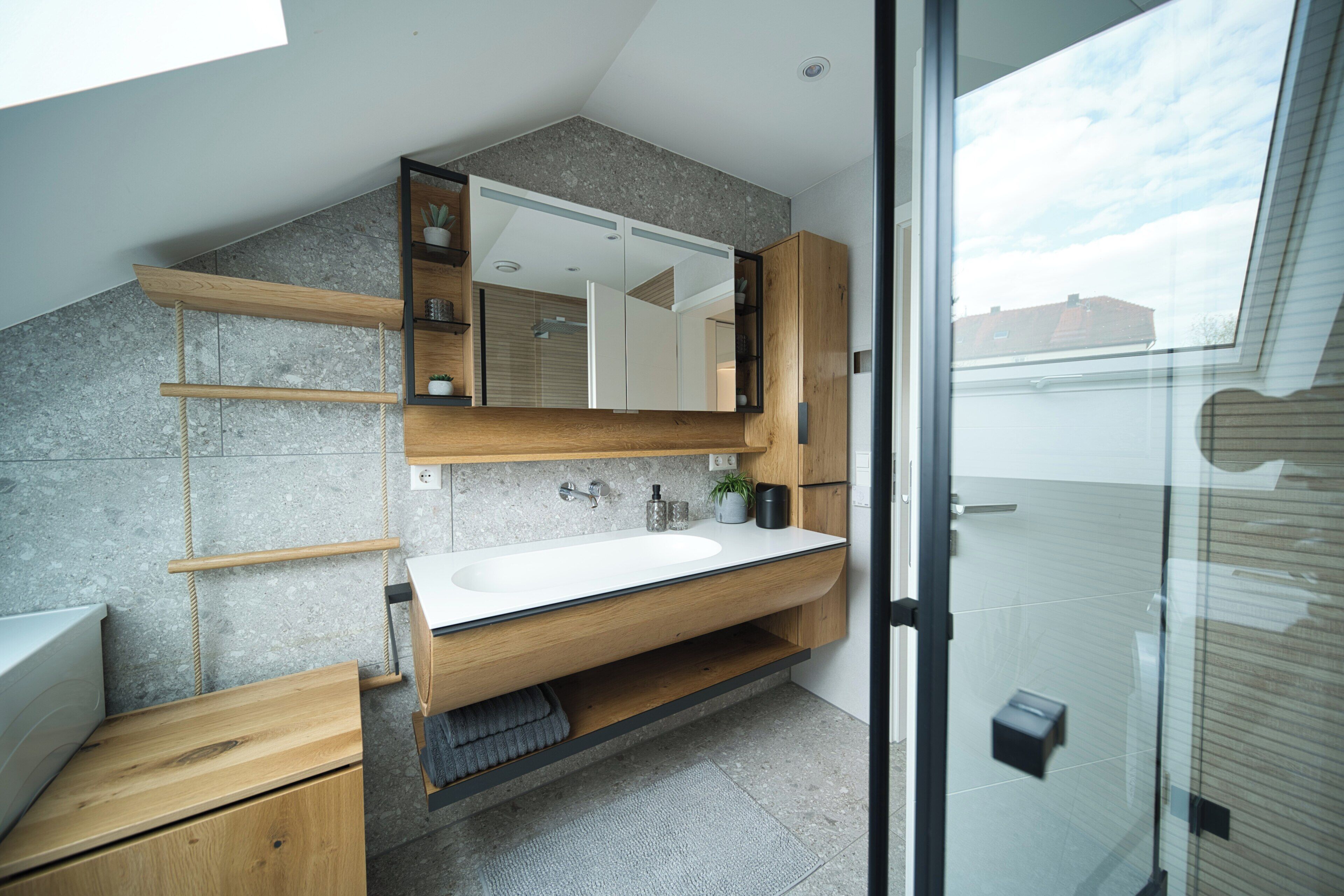 Ein modernes Badezimmer mit großem Spiegel, Holzschrank und einer Duschkabine aus Glas.