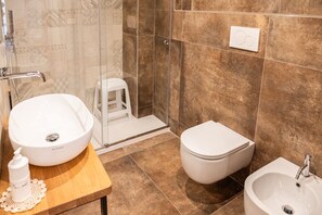 Een badkamer met een groot wit wastafel, toilet en douchehoek.