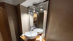 Ein Badezimmer mit einem Doppelwaschbecken, einem Spiegel mit strukturierter Rahmen und einem Handtuchhalter.
