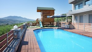 En swimmingpool med ett trädäck, en vattenrutschkana och utsikt över bergen.