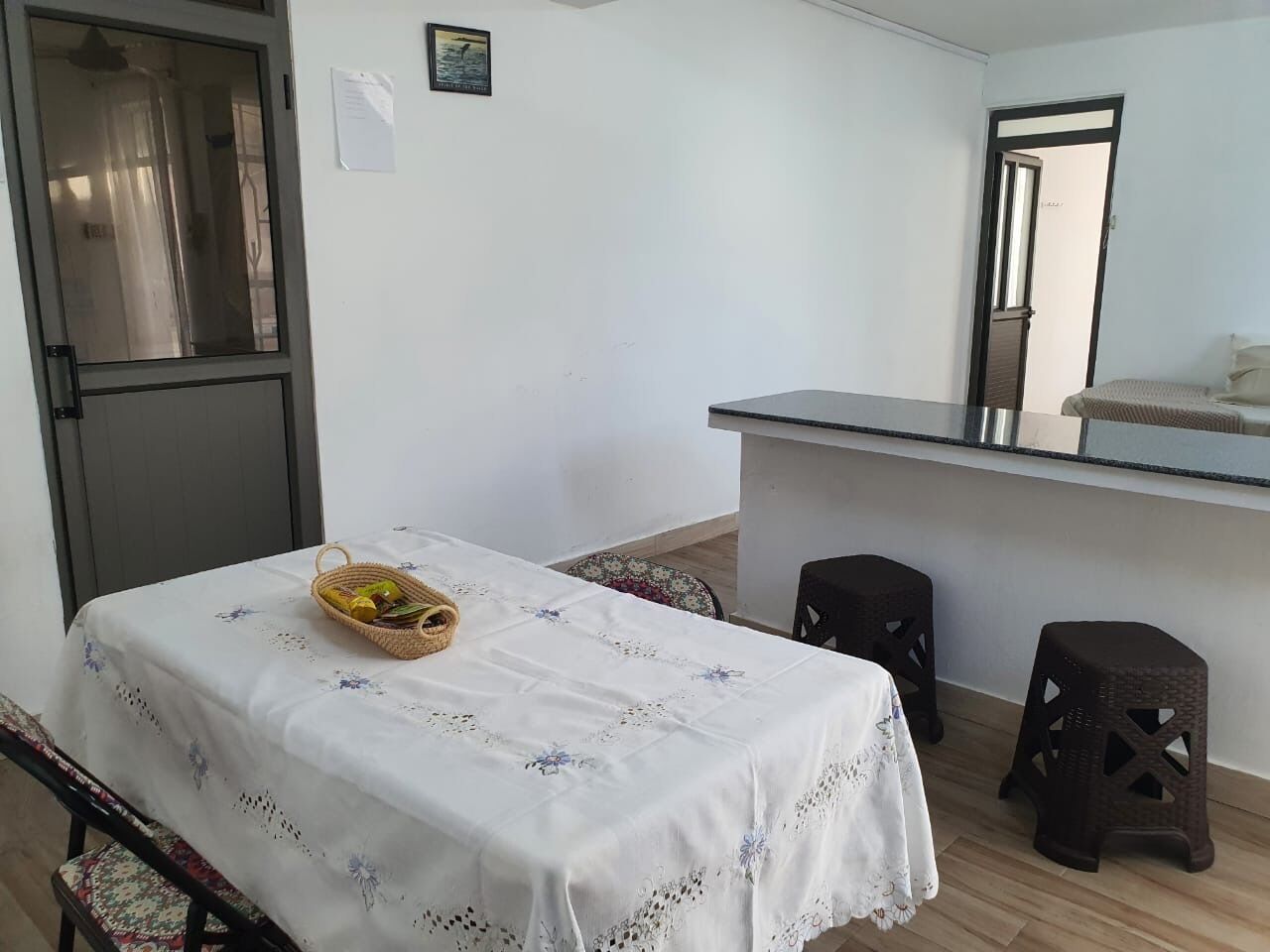 Une petite pièce propre, avec un lit, une table sur laquelle se trouve un panier, et un coin cuisine.
