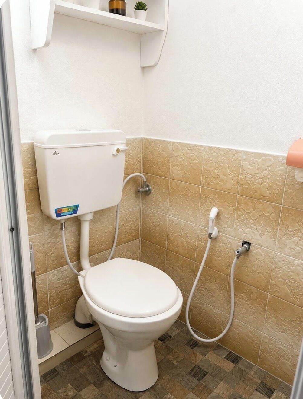 Un baño pequeño con inodoro, calentador de agua instalado en la pared y cabezal de ducha.