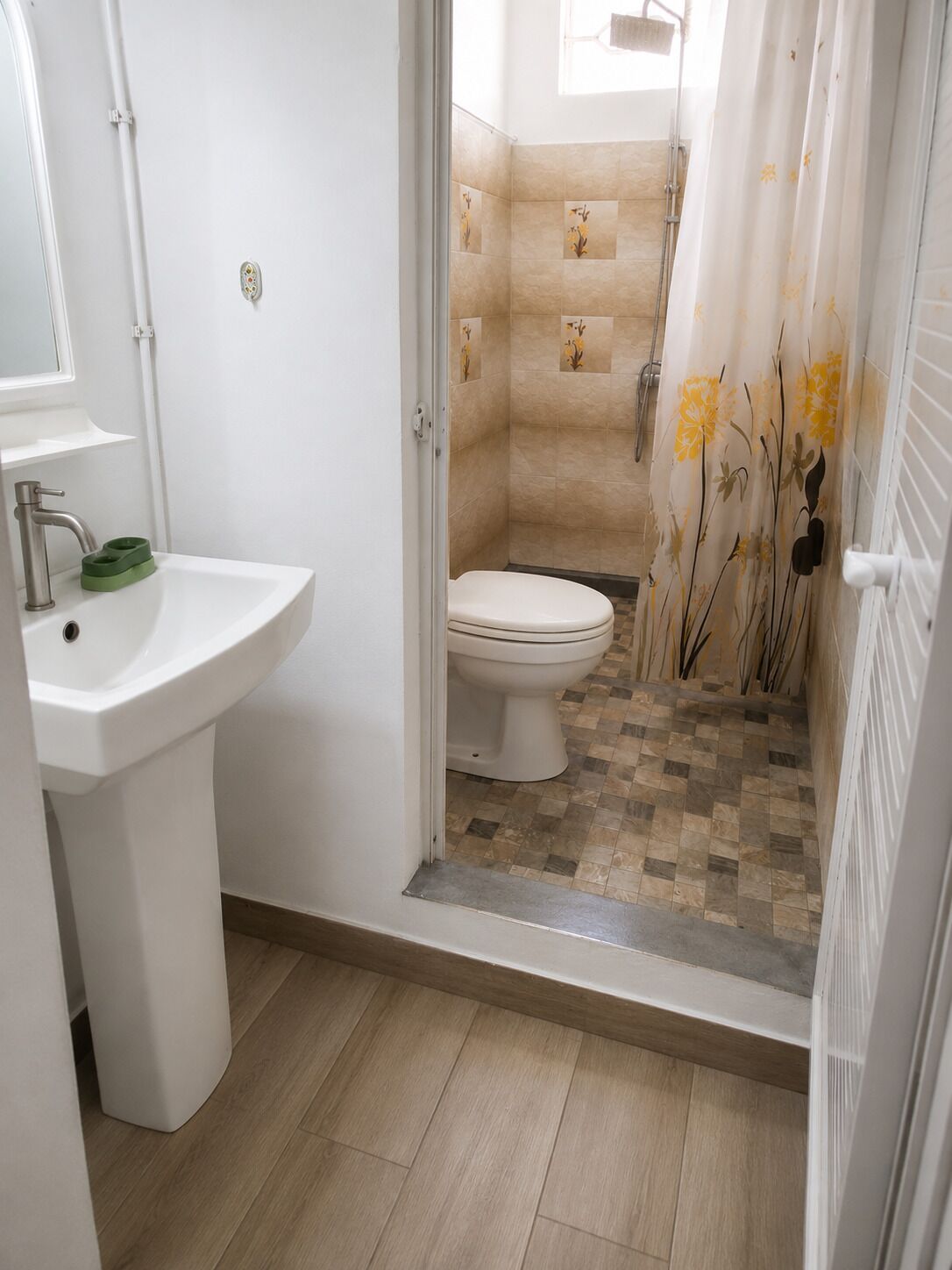 A bathroom with a white sink, toilet, and shower area.