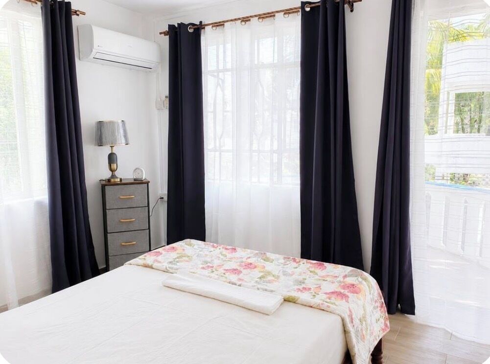 Un dormitorio con cama, cómoda y ventana con cortinas.