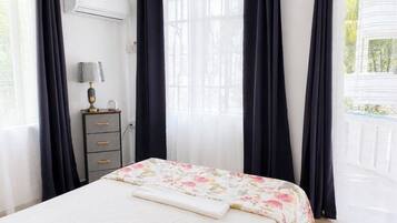 A bedroom with a bed, a dresser, and a window with curtains.