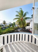 Un balcón con vistas a una zona residencial, que incluye palmeras y casas.
