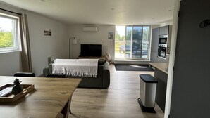 Una habitación moderna con una cama, televisión, mesa de comedor y zona de cocina.