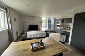 Une cuisine moderne dotée d’un four encastré, un coin repas avec une table en bois et un espace détente avec un canapé et une télévision.
