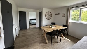 Una habitación moderna con una mesa de comedor de madera, sillas negras, un reloj de pared y una ventana con vistas a follaje.