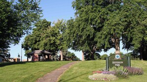 A park with a sign reading 'Jefferson Park,' a paved path, and a gazebo. - Modern 2BR Basement • Near LRT • Parking (Seattle)