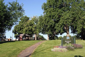 Ein Park mit einem Schild, das 'Jefferson Park' zeigt, einem gepflasterten Weg und einem Gazebo.