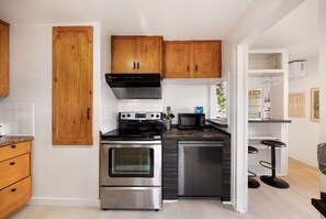 Una cocina moderna con armarios de madera, electrodomésticos de acero inoxidable y una zona de bar.
