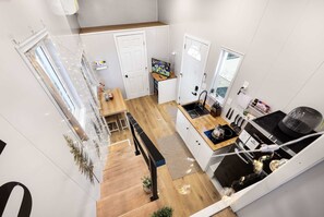 Eine moderne Küche mit Essbereich, einem kleinen Fernseher und einer Treppe, die in ein Obergeschoss führt.