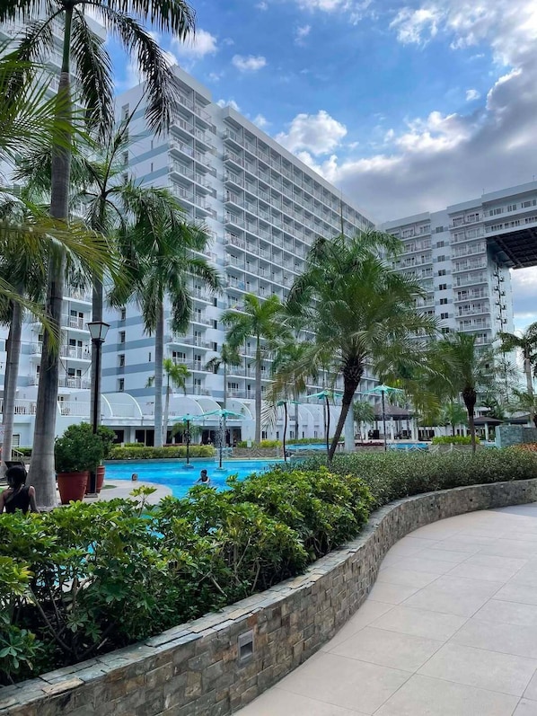 Ein Hotel mit mehreren Etagen, einem Schwimmbecken und Palmen.