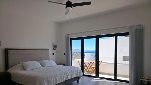 Ein Schlafzimmer mit einem Bett, einem Deckenventilator und Blick ins Freie.