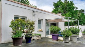 A building with a white exterior, a covered patio area, and potted plants. - Independent House 5 Minutes from the Beaches (Les Mathes)
