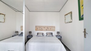 A modern bedroom with a large bed, bedside tables with lamps, a mirror, and a wall art piece. - Independent House 5 Minutes from the Beaches (Les Mathes)