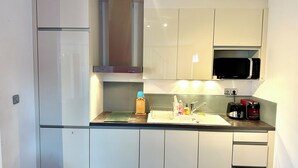 A compact kitchen with a microwave, sink, and a toaster.