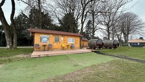 A wooden cabin with a sauna, two chairs, and two tables.