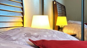 A hotel room with a bed, two bedside lamps, a wooden headboard, and a mirror.