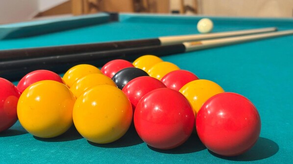 A pool table with a set of billiard balls and a cue stick.
