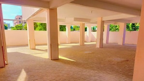 An open indoor space with a brick floor, white pillars, and a view of greenery outside. - Lux Suites Concord Apartments Mtwapa (Mtwapa)
