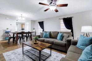 A modern living room with a sofa, coffee table, and dining area. - 7 mi Lackland BMT HotTub SeaWorld Bocce BIG Chess (San Antonio)