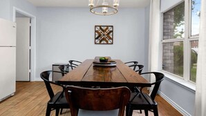 A dining area with a wooden table, black chairs, a chandelier, and a window with a view. - 8 mi Lackland AFB BMT HotTub Game Room Bocce Ball (San Antonio)