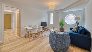 A modern living room with a dining area, a sofa, a TV, and a window. - Alexandra House by Guestz (Stockport)